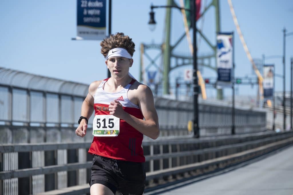 A young man in a white and red shirt runs across the Macdonald Bridge during MACPASS Miles 2022.