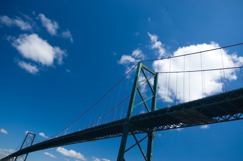 The MacKay Bridge is seen amid a bright blue sky with crisp white clouds.