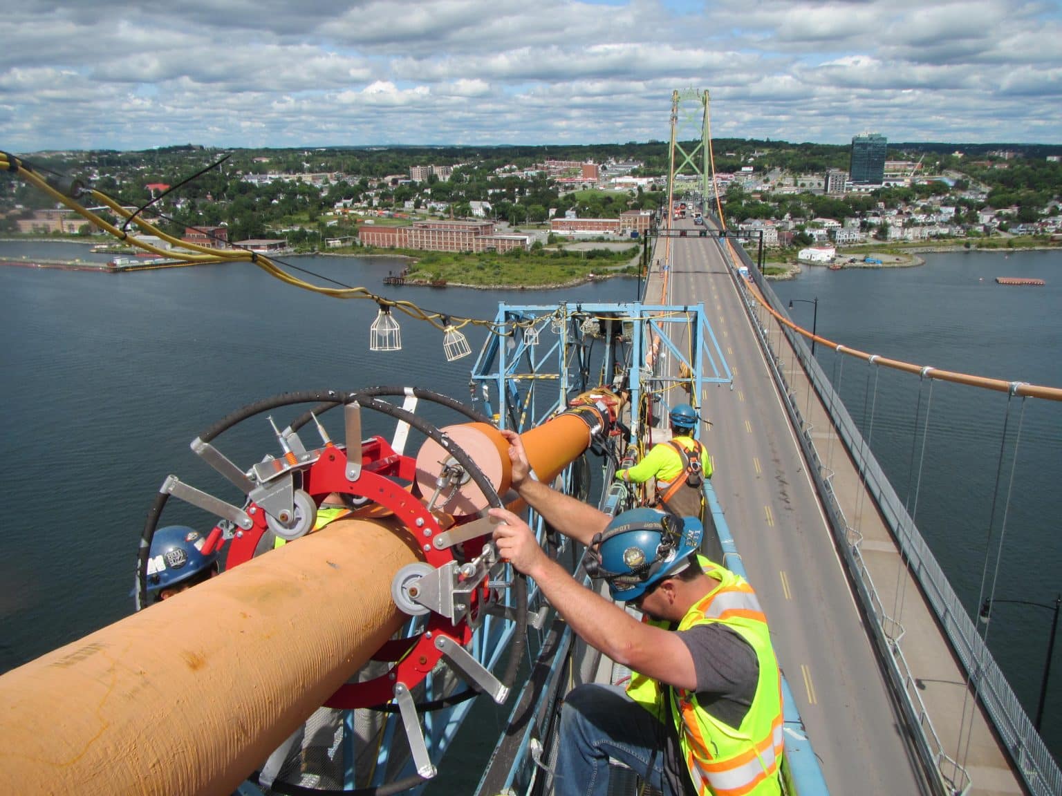 A worker installs a dehumidification device on one of the cables on the Macdonald Bridge.