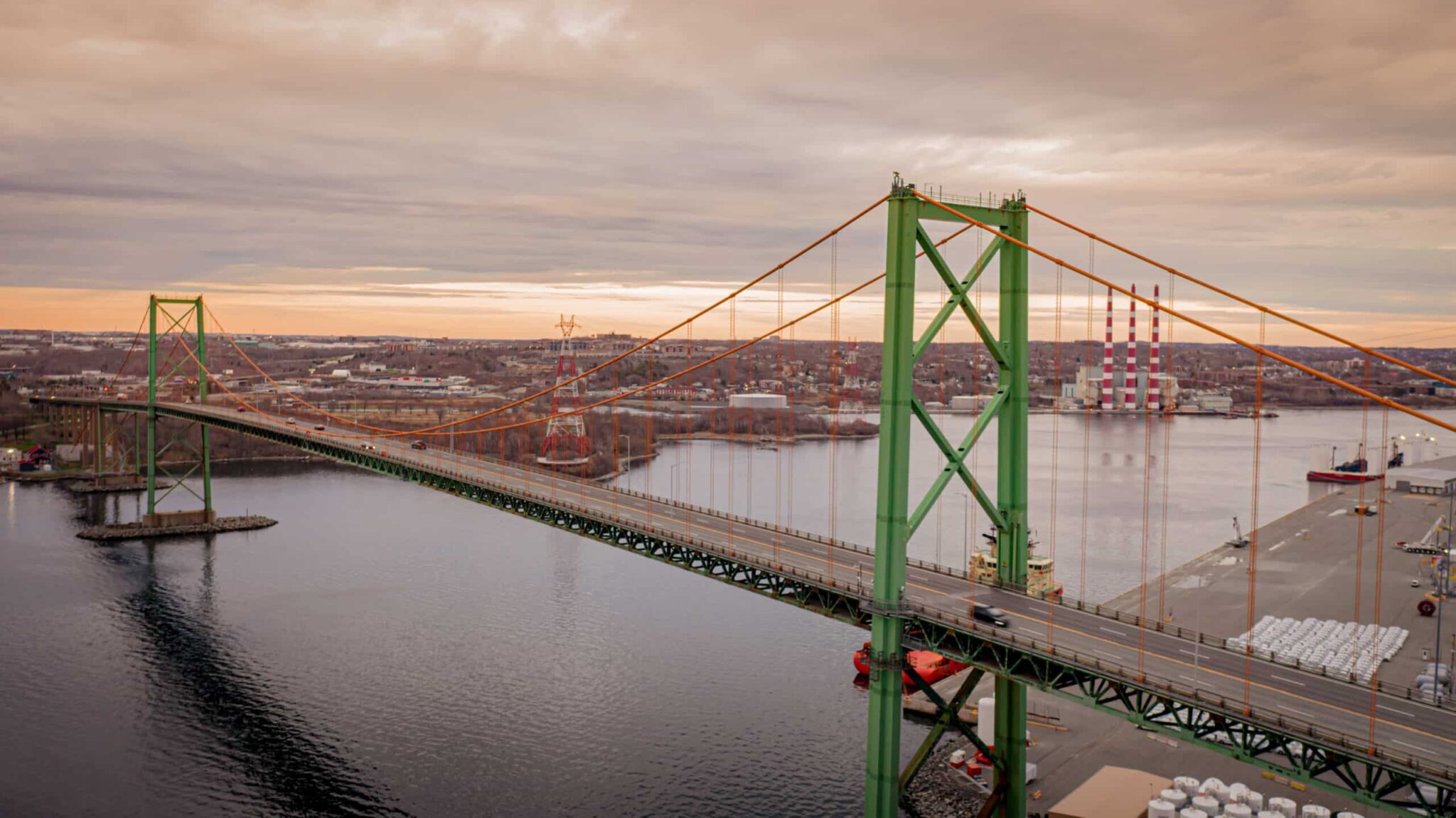 The Macdonald Bridge is seen spanning Halifax Harbour, with the red-and-white striped towers of Tufft's Cove in the background.