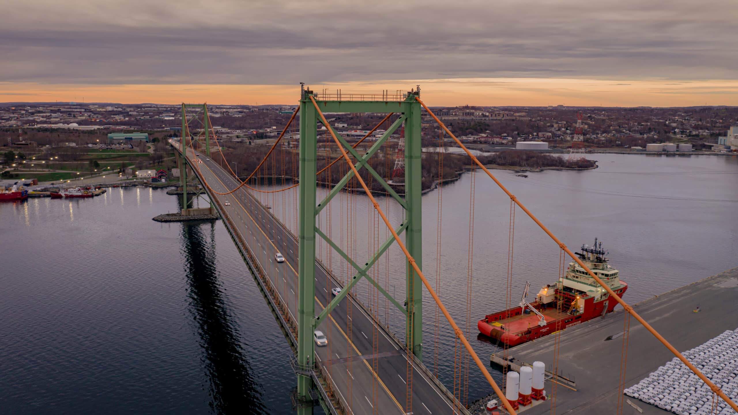 Vehicles drive on the MacKay Bridge at dusk.