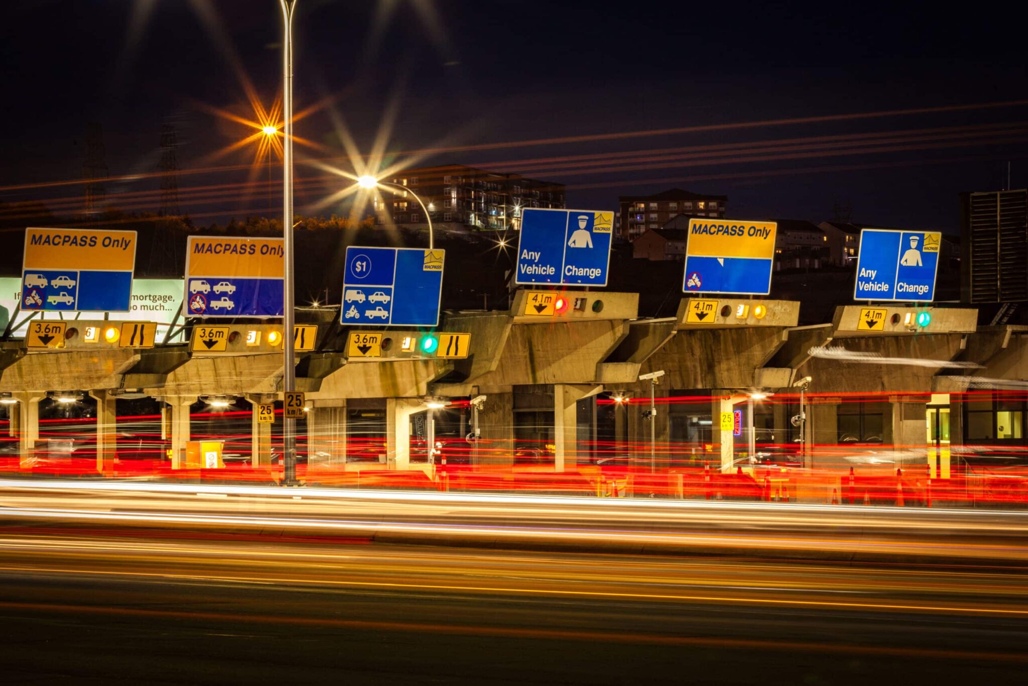 A long-exposure photo of vehicles driving through the MacKay Bridge toll booths.