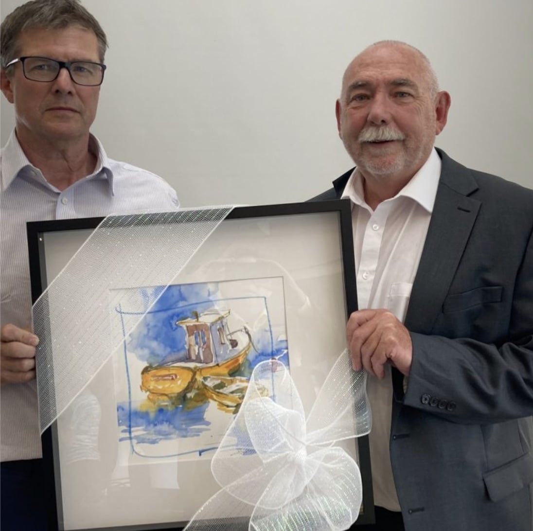 Past-CEO Steve Snider holds a piece of art presented to him by a community partner.