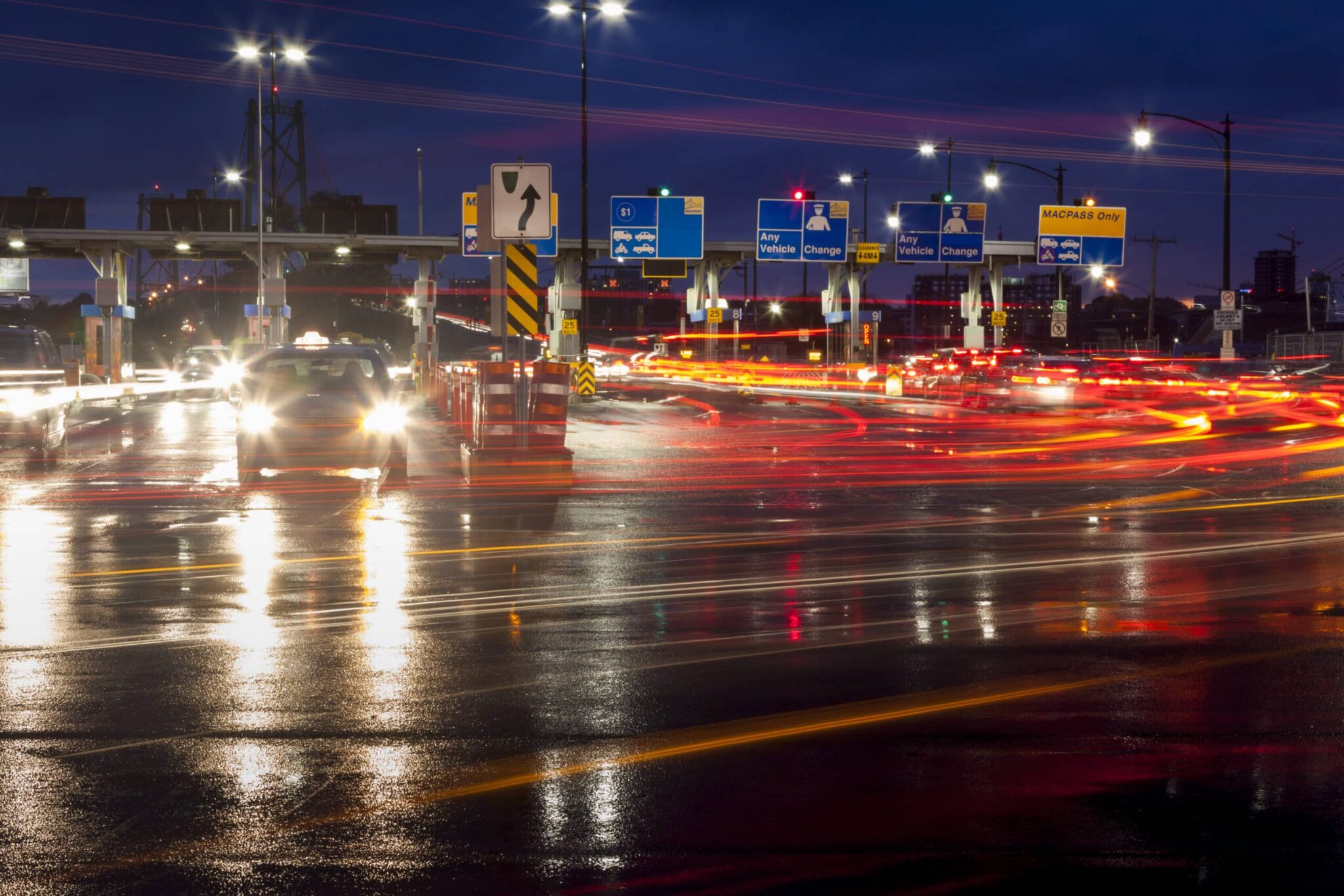 A long-exposure photo shows vehicles driving through the Macdonald Bridge tolls.