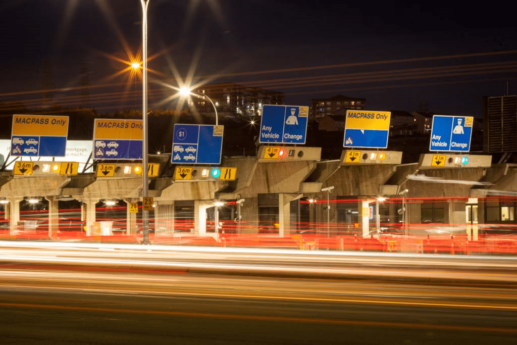 A long-exposure photo of vehicles driving through the MacKay Bridge toll booths.