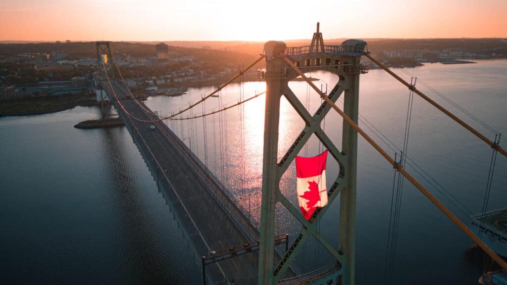 A photo of the Macdonald Bridge deck and towers, with the Canadian and Ukrainian flags flying in the towers.